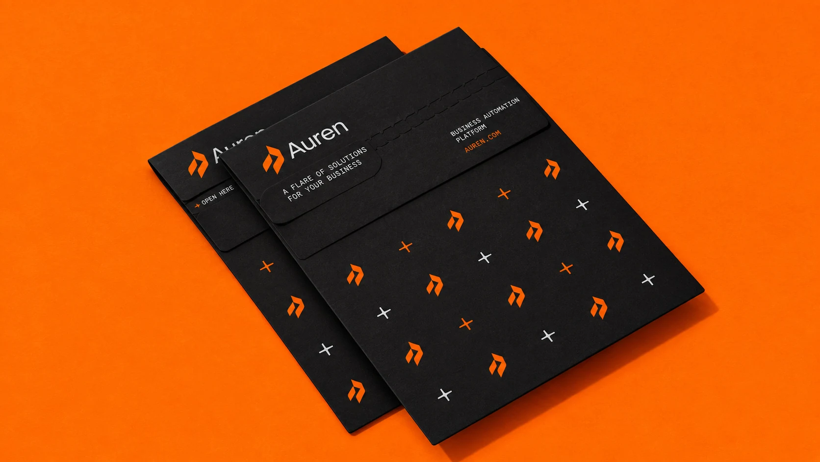 Black Auren envelopes with orange symbols and a repeating brand pattern on an orange surface.