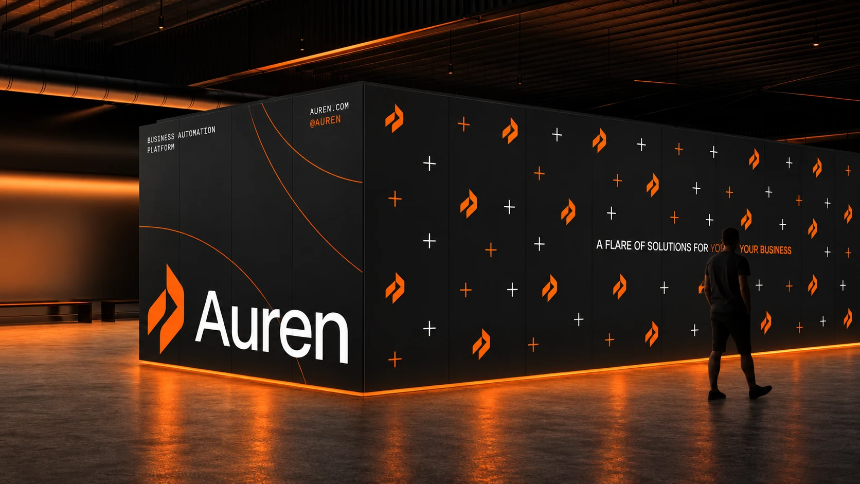 Auren's orange symbol and white wordmark across a black exhibition wall, with repeating brand marks and orange lighting.