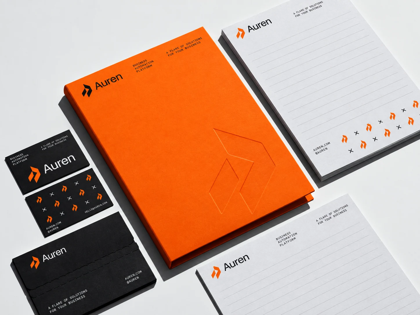 Auren stationery collection with an orange notebook, white letterheads and black business cards carrying the same symbol and pattern.
